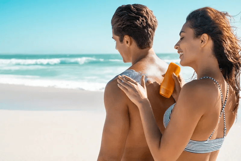 Woman applying sunscreen on man. By Rido81