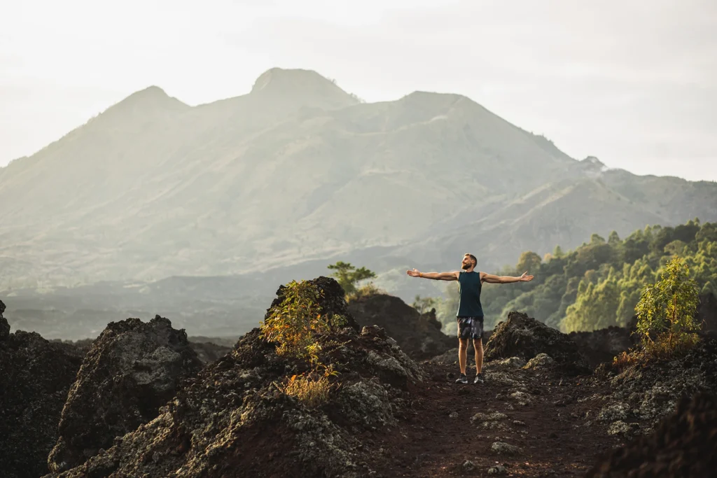 Young happy man hiking and enjoying amazing volcanic mountain Batur view in Bali. 
